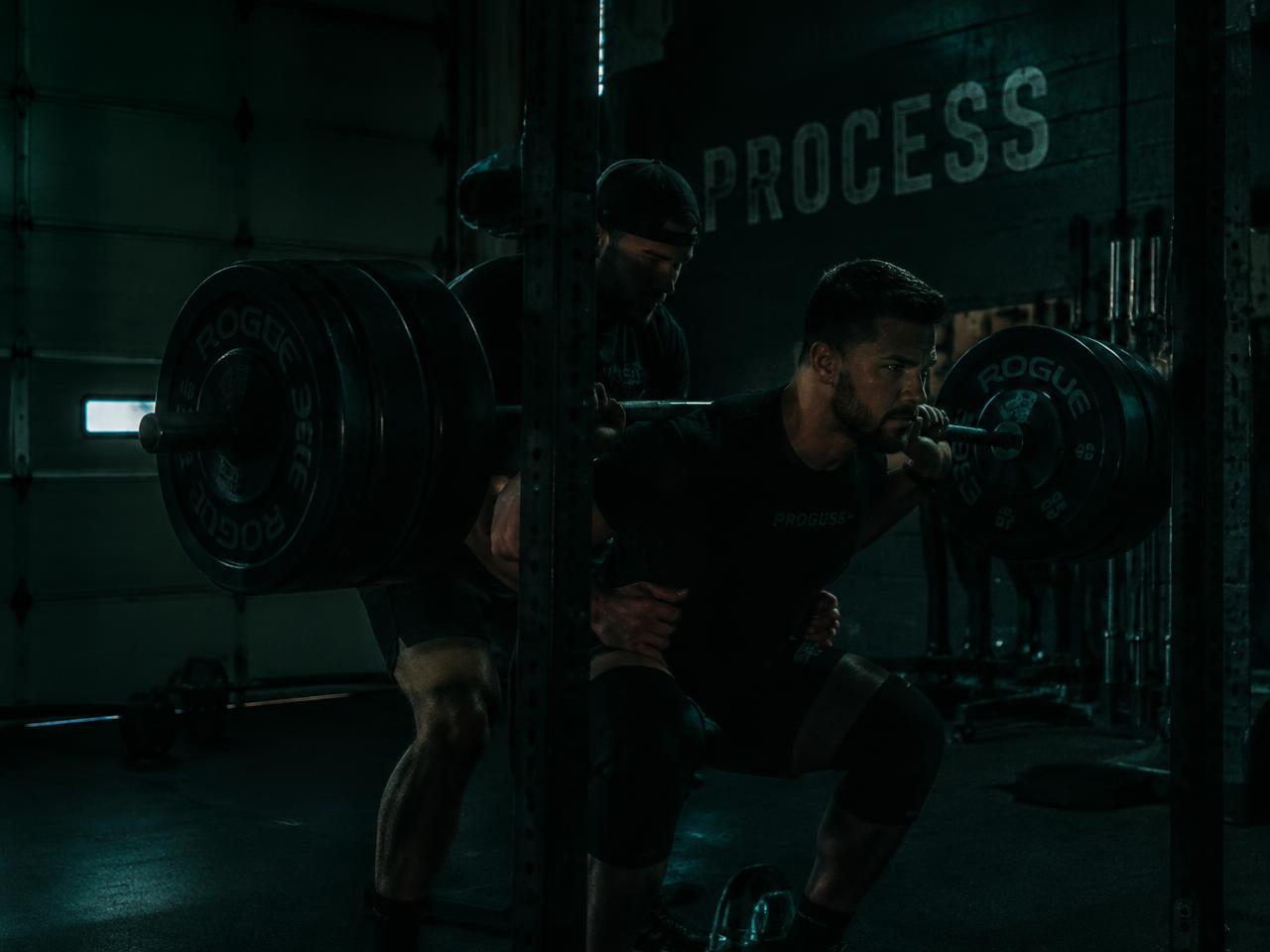Coach supporting a lifter through a heavy squat